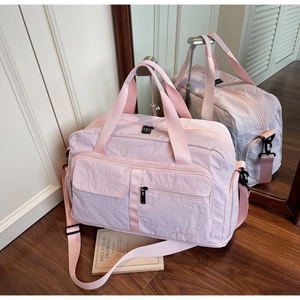 Detail of the light pink waterproof nylon travel bag with adjustable strap on wood floor