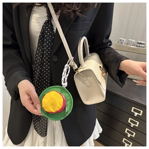 Close-up of a colorful mini round storage pouch attached to a beige handbag strap
