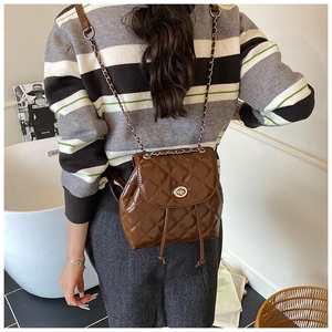 Close-up of brown quilted leather mini backpack with silver twist lock and chain strap
