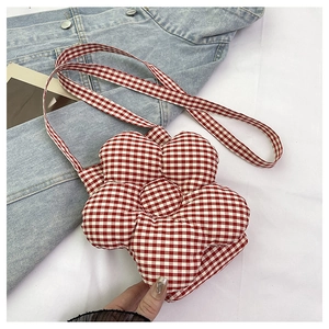 Détail d'un petit sac bandoulière en forme de fleur à carreaux rouges et blancs sur fond blanc
