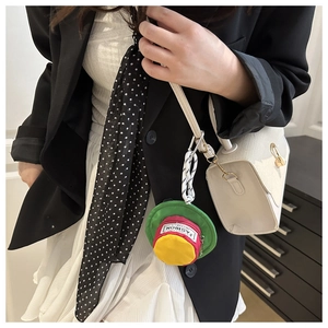 Close-up of a colorful mini hat pouch used as a creative charm on a white handbag