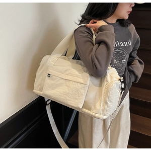 Detail view of large cream canvas travel bag with adjustable strap and side shoe compartment