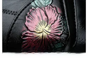 Detail of colorful floral embossing and precise stitching on black soft leather bag