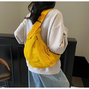 Detail of yellow canvas crescent crossbody bag with braided rope zipper pull on model