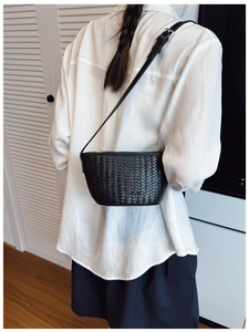 Detailed view of black woven texture crossbody bucket bag worn on a model's shoulder
