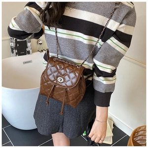 Detail of brown quilted leather backpack with metal turn-lock and chain strap