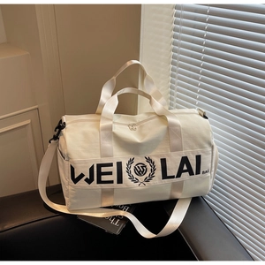 Close-up of white canvas gym bag featuring black letter logo and detachable shoulder strap