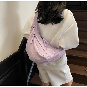 Detail of purple crescent dumpling bag with textured nylon fabric and adjustable strap