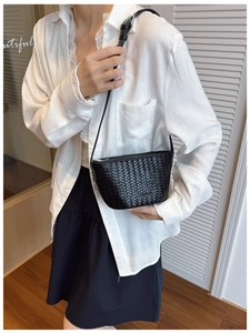 Close-up of black woven leather bucket bag texture and adjustable shoulder strap