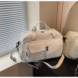 Light gray nylon travel bag detail showing zipper pockets and adjustable shoulder strap