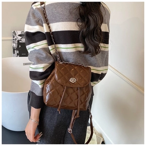 Detail shot of brown quilted mini backpack featuring chain straps and silver twist lock