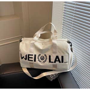 Detail of white sports duffel bag with black handles on a luxury leather sofa