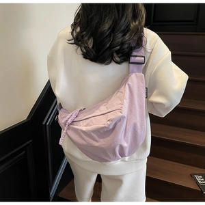 Detail of light purple nylon half-moon crossbody bag with woven rope zipper on a model