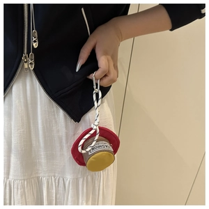 Mini hat-shaped bag with carabiner clip and rope handle, worn on blue jacket outfit