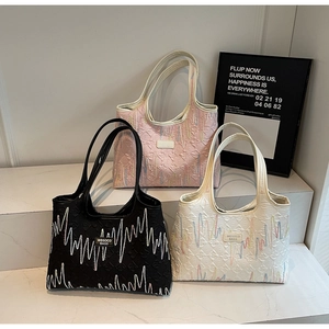 Detailed close-up of textured tote bags in black, white and pink with wave embroidery