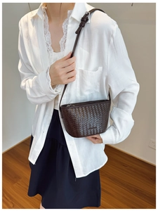 Detail of dark brown woven bucket bag showing its textured leather and adjustable strap