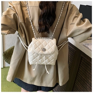 White quilted mini backpack with silver twist-lock closure and leather chain straps
