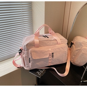 Detail of light pink travel bag with multiple pockets on a wooden surface with mirror reflection
