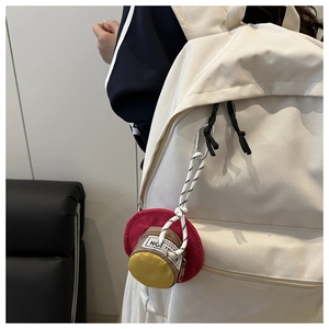 Mini hat-shaped earphone case hanging on a white backpack with silver carabiner