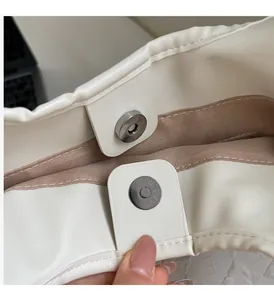 Close-up of the magnetic hardware closure on a beige faux leather tote bag