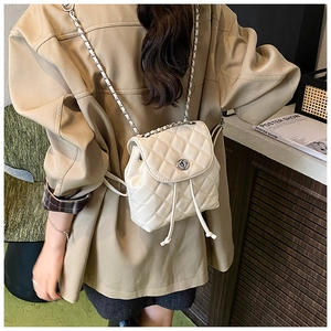 Close-up of cream quilted mini backpack with leather-interwoven chain strap details