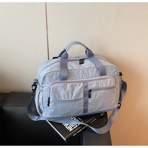 Detail of light blue waterproof travel bag showing front pockets and nylon texture