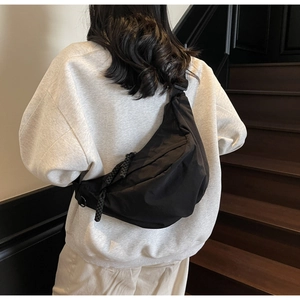 Detail of black waterproof nylon crescent bag with braided rope zipper pull decoration