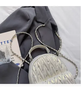 Detail of pearl white quilted PU backpack with rhinestone accents and chain strap