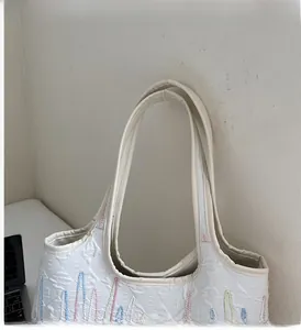 Detailed view of the quilted tote bag showing sturdy handles and colorful wave embroidery