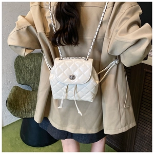 Detail shot of white quilted mini backpack with metal chain straps and twist lock closure