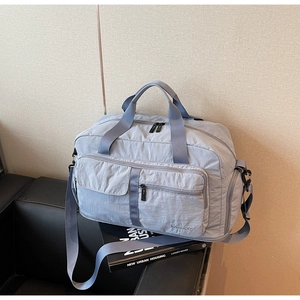 Close-up of light blue travel bag with dual handles and adjustable strap on a sofa