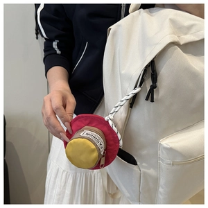 Detail showing the hat-shaped mini coin purse attached to a backpack with a woven strap