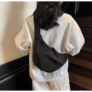Detail of black crescent crossbody bag showing waterproof nylon texture and woven zipper