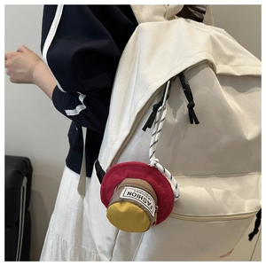 Close-up of a hat-shaped mini earphone pouch hanging on a white backpack for daily use