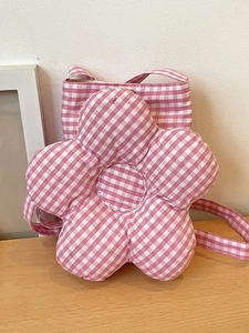 Sac bandoulière en forme de fleur à carreaux rose et blanc avec centre matelassé sur table