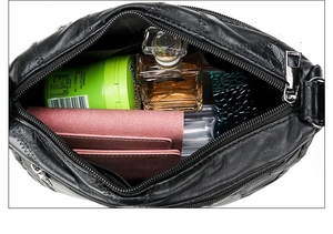 Spacious interior of black leather shoulder bag with inner zipper pocket and items