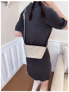 Detail of beige woven bucket bag with smooth strap on a grey knit dress