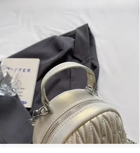 Close-up of cream pleated handbag featuring rhinestone accents and a durable handle