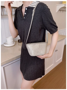 Detailed view of silver woven bucket bag worn with a casual dark grey knitted dress