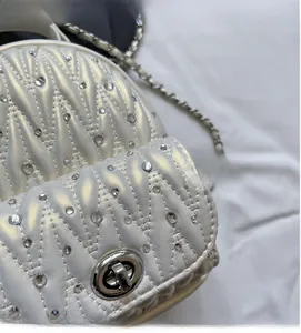 Detail of pearlescent white V-quilted bag with embedded rhinestones and silver metal twist lock