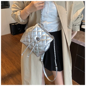 Detailed close-up of a silver quilted backpack with a metallic finish and chain strap