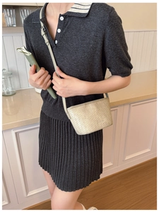 Detail of a beige woven leather bucket bag with an adjustable strap worn by a model