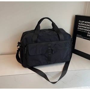 Detailed view of black travel bag showing waterproof nylon texture and multi-pocket layout
