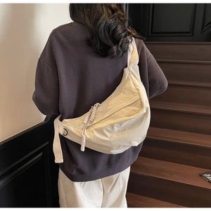Detail of off-white crescent crossbody bag with pleated texture and rope zipper detail