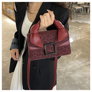 Detail of burgundy leopard print handbag with black square buckle and knotted handle