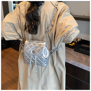 Detail of silver quilted mini backpack with chain straps and metallic twist lock