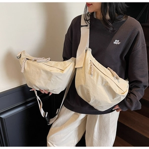 Detail of cream nylon crescent bags with woven zipper pulls and wide shoulder straps