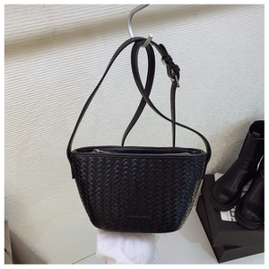 Detail of woven black bucket bag featuring textured leather and brand logo imprint