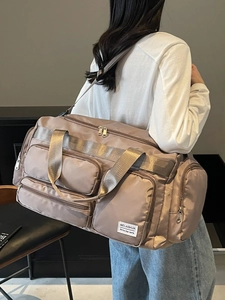 Grande borsa da viaggio marrone moka con design impermeabile multi-tasche indossata da modello