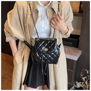 Detail of black quilted leather mini backpack with silver chain straps on a model